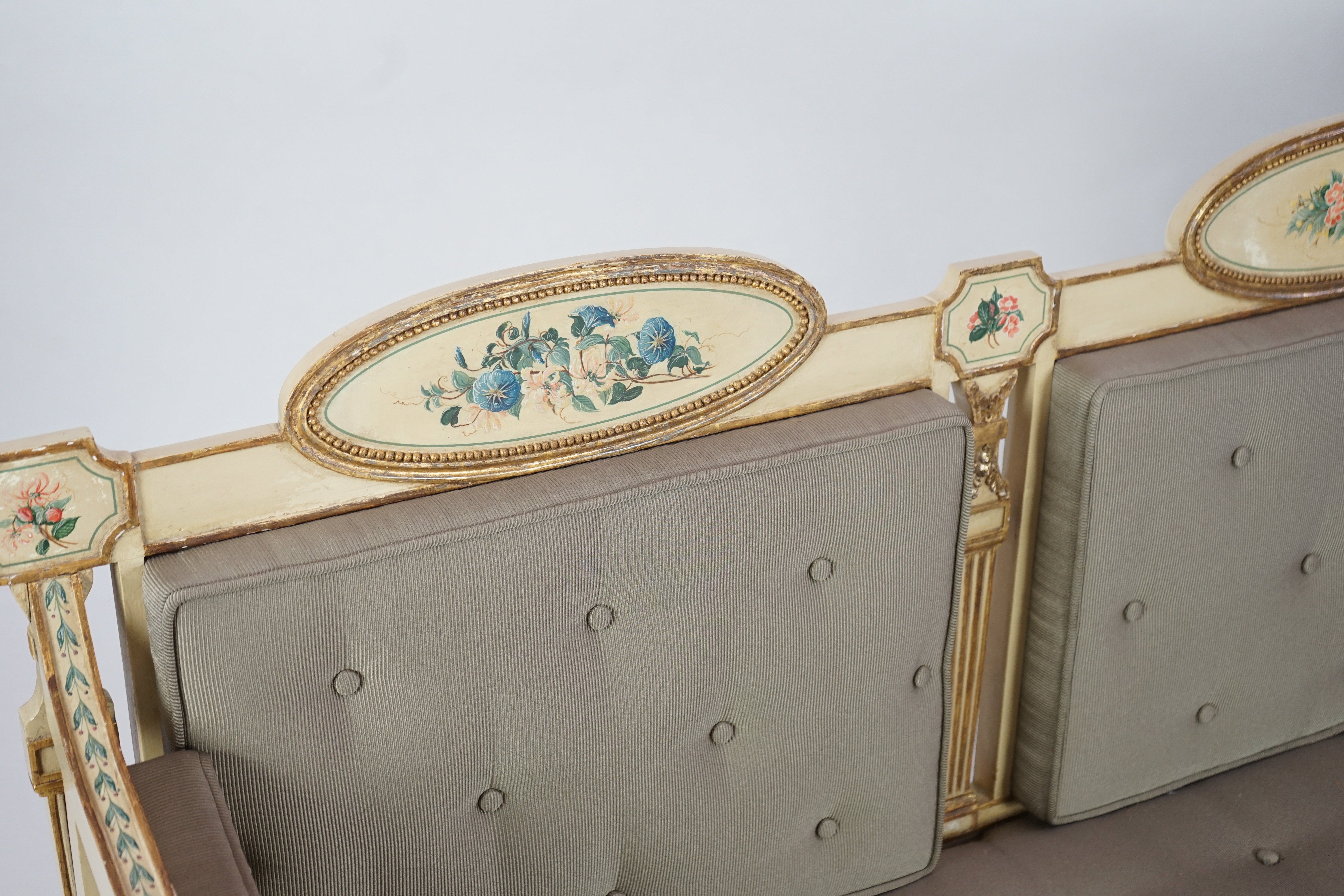 A pair of George III cream painted and parcel gilt settees, in the manner of George Brookshaw (1751-1823)